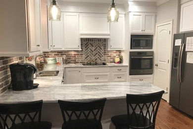 Large transitional u-shaped medium tone wood floor and brown floor eat-in kitchen photo in Birmingham with a double-bowl sink, shaker cabinets, white cabinets, multicolored backsplash, stainless steel appliances and a peninsula