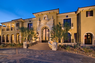 Expansive traditional two-storey beige house exterior in Phoenix with stone veneer, a flat roof and a tile roof.