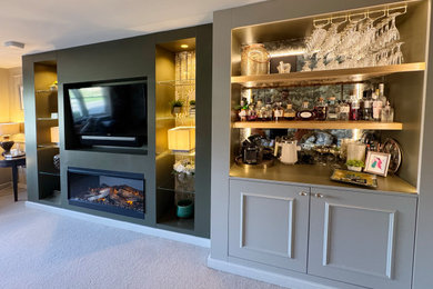 This is an example of a medium sized modern games room in Other with beige walls, carpet, a built-in media unit and beige floors.