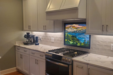 Modelo de cocina contemporánea con salpicadero blanco, salpicadero de azulejos tipo metro, electrodomésticos de acero inoxidable, suelo marrón y encimeras blancas
