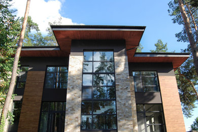 Imagen de fachada de casa gris y negra actual grande de tres plantas con revestimientos combinados, tejado de metal y tejado a cuatro aguas