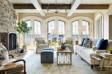 Living room - french country enclosed medium tone wood floor, brown floor and exposed beam living room idea in Minneapolis with beige walls, a standard fireplace, a stone fireplace and no tv