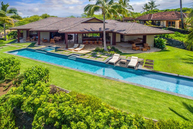 Imagen de piscina alargada de estilo americano grande rectangular en patio trasero con paisajismo de piscina y adoquines de piedra natural