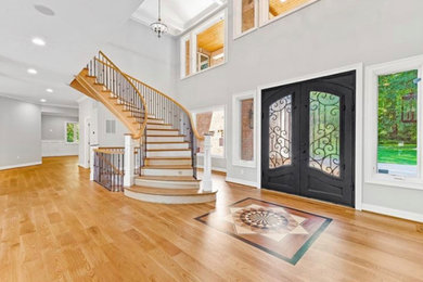 Entryway - huge traditional medium tone wood floor and brown floor entryway idea in Other with gray walls and a black front door