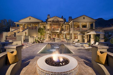 Photo of an expansive mediterranean backyard patio in Phoenix with a fire feature, natural stone pavers and a pergola.