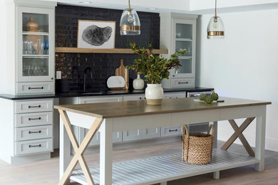 Wet bar - mid-sized cottage single-wall medium tone wood floor and beige floor wet bar idea in Indianapolis with an undermount sink, shaker cabinets, white cabinets, wood countertops, black backsplash, subway tile backsplash and beige countertops