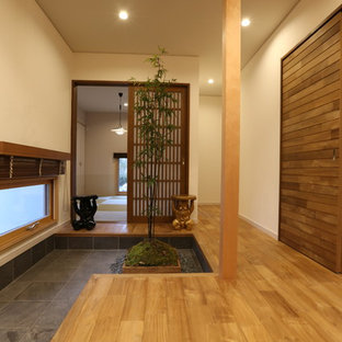 他の地域の片開きドアアジアンスタイルのおしゃれな玄関ホール (白い壁、濃色無垢フローリング、茶色いドア) の写真