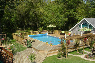 Example of a large minimalist backyard custom-shaped lap pool design in Detroit with decking