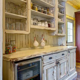 Cette image montre une petite arrière-cuisine parallèle chalet avec un évier encastré, un placard avec porte à panneau encastré, des portes de placard en bois vieilli, un plan de travail en granite, une crédence beige, un électroménager en acier inoxydable, un sol en bois foncé et un îlot central.