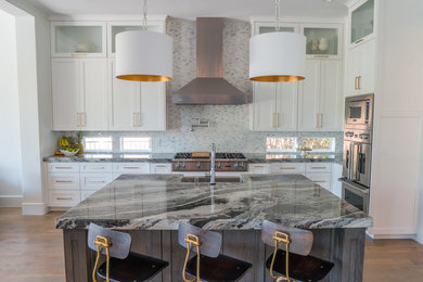 This is an example of a large modern kitchen in Dallas with an undermount sink, recessed-panel cabinets, white cabinets, quartzite benchtops, grey splashback, stone tile splashback, stainless steel appliances, dark hardwood floors, with island and brown floor.