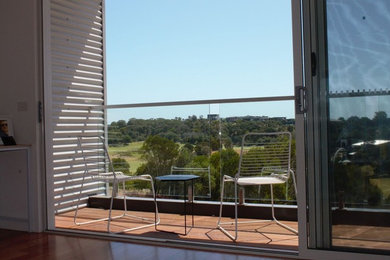 Photo of a contemporary balcony in Melbourne with an awning and glass railing.