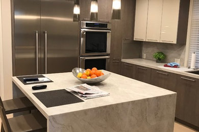 Example of a minimalist u-shaped light wood floor and beige floor enclosed kitchen design in Orange County with flat-panel cabinets, brown cabinets, an island, an undermount sink, quartz countertops, quartz backsplash, stainless steel appliances, multicolored backsplash and multicolored countertops