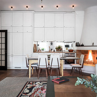 Inspiration för stora minimalistiska kök med matplatser, med vita väggar, mörkt trägolv, en öppen hörnspis och en spiselkrans i gips