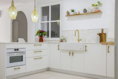 Ejemplo de cocinas en U ecléctico de tamaño medio abierto con fregadero sobremueble, puertas de armario blancas, electrodomésticos blancos, península y suelo blanco