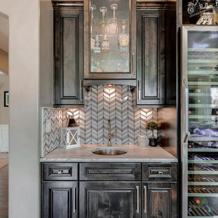 デンバーの小さいコンテンポラリースタイルのおしゃれなウェットバー (アンダーカウンターシンク、ルーバー扉のキャビネット、濃色木目調キャビネット、クオーツストーンカウンター、白いキッチンパネル、ガラスタイルのキッチンパネル、無垢フローリング、茶色い床、白いキッチンカウンター) の写真