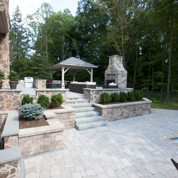 Brick paver pool deck, outdoor fireplace and kitchen on raised bluestone patio