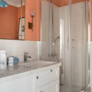 Idee per una piccola stanza da bagno con doccia boho chic con ante con bugna sagomata, ante bianche, doccia ad angolo, WC sospeso, piastrelle arancioni, piastrelle in ceramica, pareti arancioni, pavimento con piastrelle in ceramica, lavabo integrato, top in superficie solida, pavimento grigio, porta doccia scorrevole e top beige