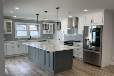 Eat-in kitchen - contemporary ceramic tile and brown floor eat-in kitchen idea in New York with an undermount sink, shaker cabinets, white cabinets, quartzite countertops, gray backsplash, glass tile backsplash, stainless steel appliances, an island and white countertops