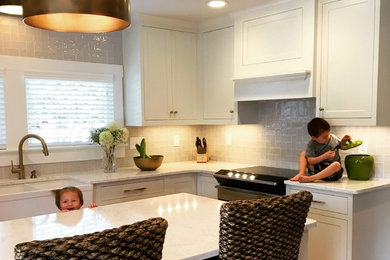 Open concept kitchen - mid-sized transitional u-shaped light wood floor and brown floor open concept kitchen idea in Other with a farmhouse sink, recessed-panel cabinets, white cabinets, quartz countertops, beige backsplash, ceramic backsplash, stainless steel appliances and an island
