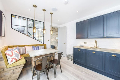 Design ideas for a medium sized contemporary l-shaped kitchen/diner in London with a submerged sink, shaker cabinets, blue cabinets, concrete worktops, white splashback, stainless steel appliances and grey floors.