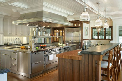 Huge ornate medium tone wood floor eat-in kitchen photo in New York with beaded inset cabinets, stainless steel cabinets, metallic backsplash, stainless steel appliances, a drop-in sink, metal backsplash, two islands and stainless steel countertops