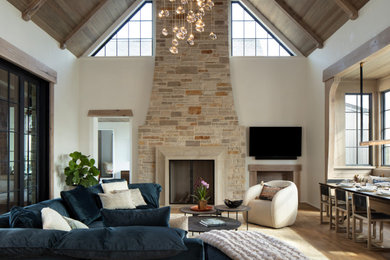 Идея дизайна: открытая гостиная комната в стиле кантри с белыми стенами, паркетным полом среднего тона, стандартным камином, фасадом камина из камня, телевизором на стене, коричневым полом, сводчатым потолком и деревянным потолком