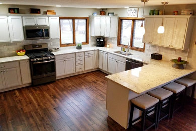 Inspiration for a large timeless u-shaped dark wood floor and brown floor open concept kitchen remodel in Chicago with a double-bowl sink, shaker cabinets, white cabinets, beige backsplash, stone tile backsplash, stainless steel appliances and a peninsula