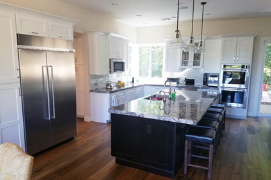 Large transitional l-shaped medium tone wood floor eat-in kitchen photo in Phoenix with an undermount sink, shaker cabinets, white cabinets, granite countertops, gray backsplash, subway tile backsplash, stainless steel appliances and an island