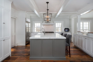Large trendy u-shaped dark wood floor and brown floor enclosed kitchen photo in New York with an undermount sink, shaker cabinets, white cabinets, quartz countertops, white backsplash, subway tile backsplash, stainless steel appliances and an island