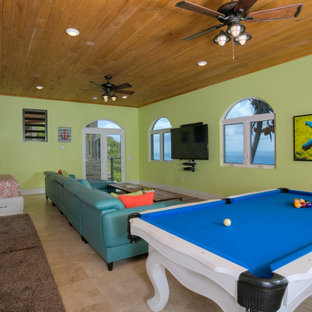 Cette image montre une très grande salle de cinéma marine ouverte avec un mur vert, un sol en travertin, un téléviseur fixé au mur et un sol beige.