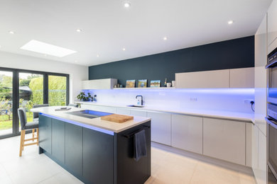 Photo of a mid-sized modern u-shaped separate kitchen in Sussex with flat-panel cabinets, quartzite benchtops, white splashback, engineered quartz splashback, with island and white benchtop.