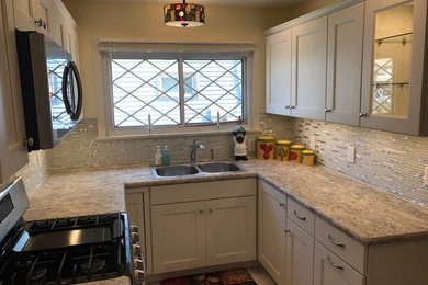 Enclosed kitchen - small transitional u-shaped limestone floor and gray floor enclosed kitchen idea in Other with a drop-in sink, recessed-panel cabinets, white cabinets, laminate countertops, white backsplash, mosaic tile backsplash, stainless steel appliances and no island