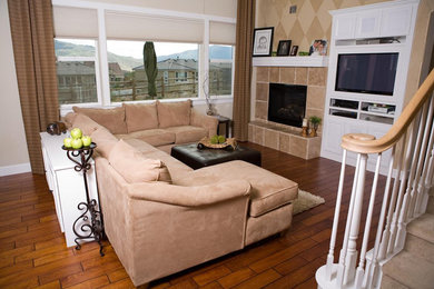 Family room - mid-sized traditional open concept medium tone wood floor family room idea in Other with beige walls, a standard fireplace, a tile fireplace and a media wall