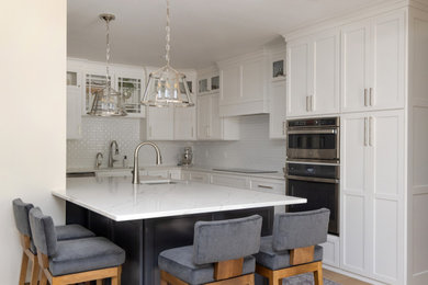 Mid-sized transitional l-shaped medium tone wood floor and brown floor open concept kitchen photo in Other with an undermount sink, gray cabinets, quartz countertops, white backsplash, subway tile backsplash, stainless steel appliances, a peninsula, white countertops and shaker cabinets