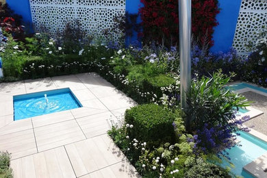 This is an example of a mediterranean xeriscape full sun garden in Surrey with a water feature and natural stone paving.