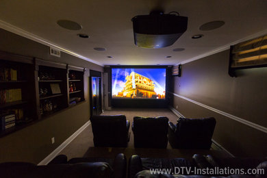 This is an example of an enclosed home theatre in New York with brown walls and a projector screen.