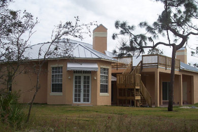 Large tuscan beige two-story stucco house exterior photo in Miami with a metal roof