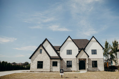 Transitional white two-story board and batten house exterior idea in Chicago with a black roof