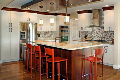 Inspiration for a timeless medium tone wood floor kitchen remodel in Denver with an undermount sink, shaker cabinets, white cabinets, granite countertops, multicolored backsplash, stone tile backsplash, stainless steel appliances and an island