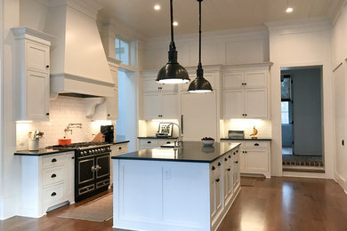 Eat-in kitchen - large farmhouse u-shaped dark wood floor and brown floor eat-in kitchen idea in Atlanta with a farmhouse sink, recessed-panel cabinets, white cabinets, soapstone countertops, white backsplash, subway tile backsplash, paneled appliances, an island and black countertops