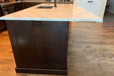 Example of a mid-sized transitional l-shaped eat-in kitchen design in Other with shaker cabinets, brown cabinets, quartz countertops, an island and white countertops