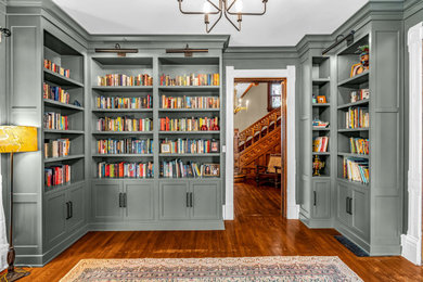 Example of a large ornate built-in desk medium tone wood floor and brown floor home office library design in Indianapolis with green walls, a standard fireplace and a stone fireplace