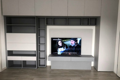 Ispirazione per un soggiorno moderno con libreria, pareti bianche, pavimento in gres porcellanato, TV a parete e pavimento grigio