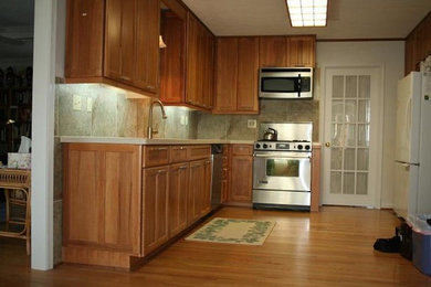 Enclosed kitchen - mid-sized traditional l-shaped light wood floor enclosed kitchen idea in Other with medium tone wood cabinets, ceramic backsplash, recessed-panel cabinets, laminate countertops, beige backsplash, stainless steel appliances, no island and an undermount sink