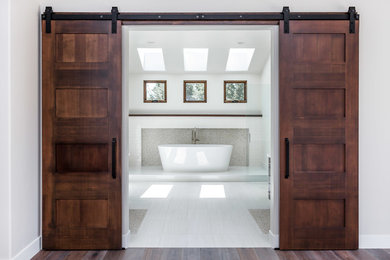 Large transitional master beige tile and pebble tile porcelain tile freestanding bathtub photo in Sacramento with white walls