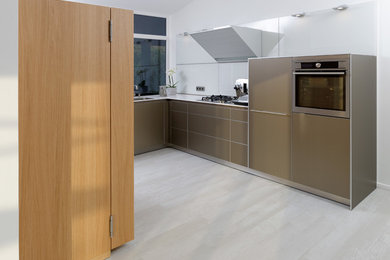 Photo of a mid-sized contemporary l-shaped separate kitchen in Bremen with no island, an undermount sink, flat-panel cabinets, light wood cabinets, quartz benchtops, white splashback, glass sheet splashback, stainless steel appliances, light hardwood floors and white floor.
