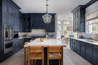 Example of a kitchen design in New York with recessed-panel cabinets, blue cabinets, stainless steel appliances and an island