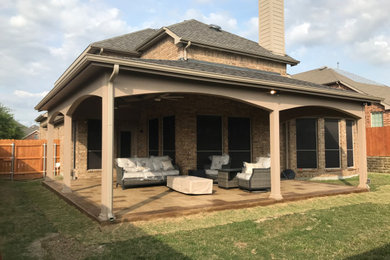 Photo of a large arts and crafts backyard patio in Dallas with stamped concrete and a roof extension.