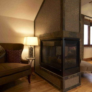 Exempel på ett stort rustikt huvudsovrum, med mellanmörkt trägolv, en dubbelsidig öppen spis, en spiselkrans i trä och beige väggar