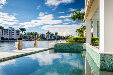 Photo of an expansive beach style backyard rectangular pool in Miami with a water feature and natural stone pavers.